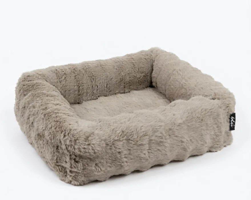 The Bliss Bed in Oat — an oatmeal-beige bolster bed in deep, plush faux fur.